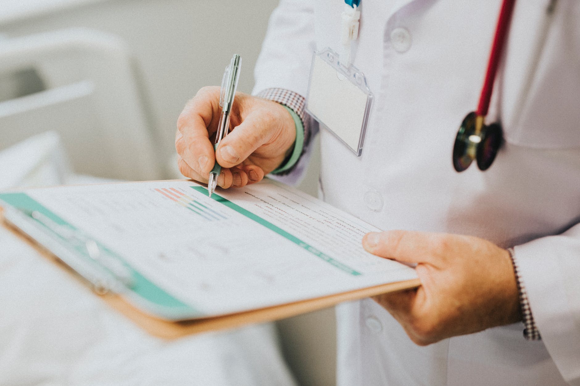 Doctor in a white lab coat standing and filling out a medical form